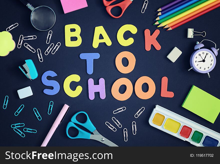 On a black background, school and office supplies are chaotically arranged. In the center is the inscription BACK TO SCHOOL, made in multi-colored letters. Beautiful pictures on top, layout.