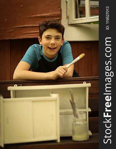 Teen boy with brush painting old furniture