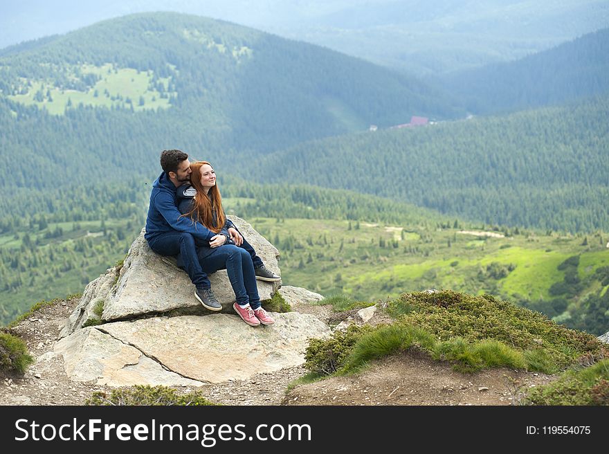 Photo of Couple Sitting on Rock