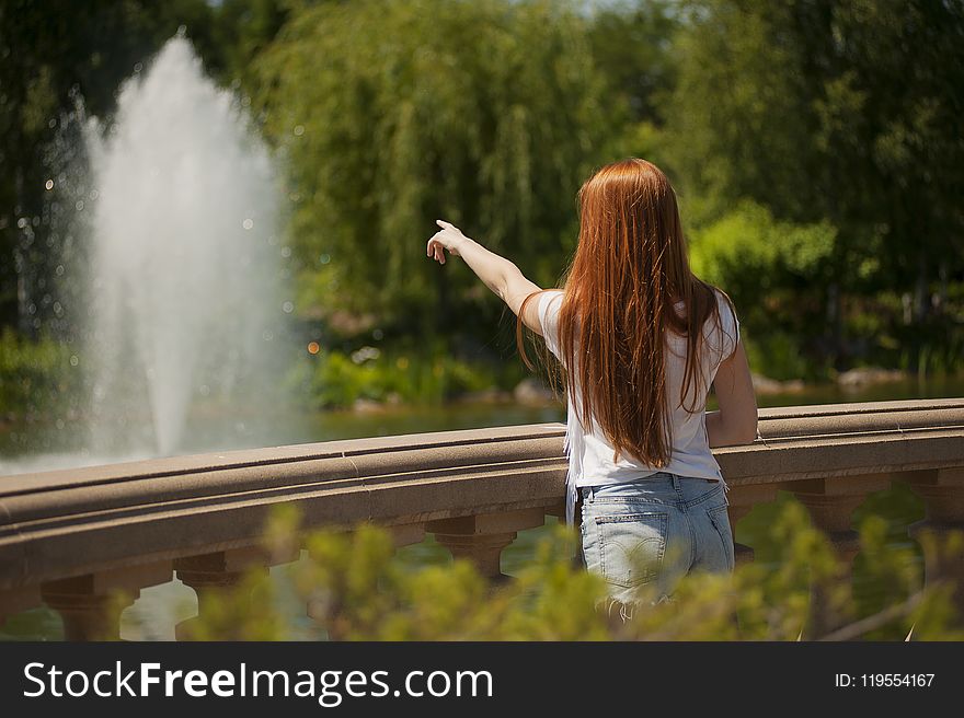 Shallow Focus Photo of Woman Standing in Front of Body of Water With Fountain