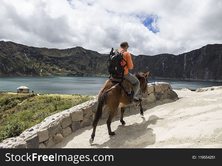 Man carrying a bag pack Riding a Brown Horse
