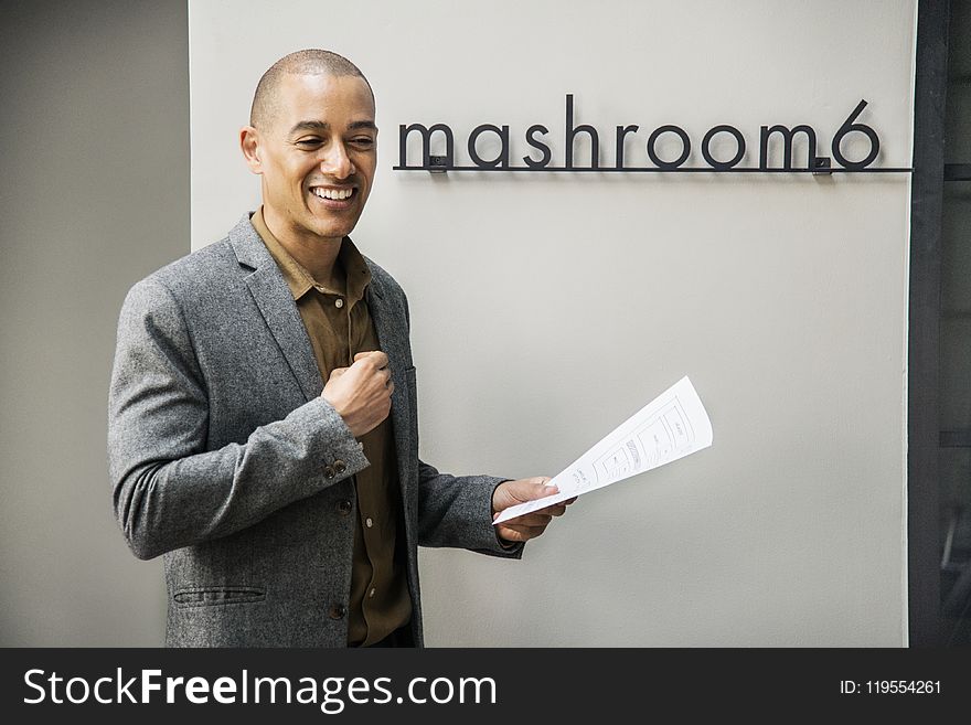 Man Wearing Grey Notched Lapel Suit Jacket Holding White Printer Paper While Standing