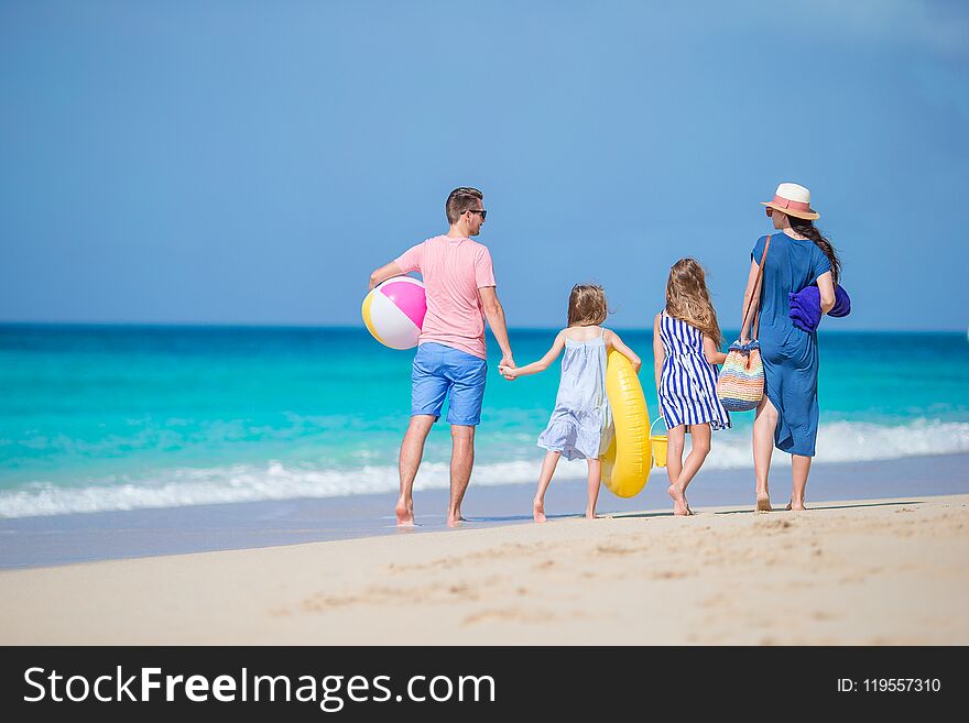 Happy beautiful family of four on white beach walking together. Happy beautiful family of four on white beach walking together