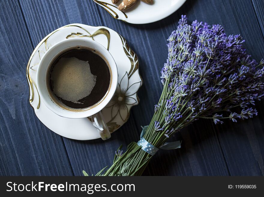 A cup of coffee and bouquet of lavender on a dark blue wooden table. Romantic background.