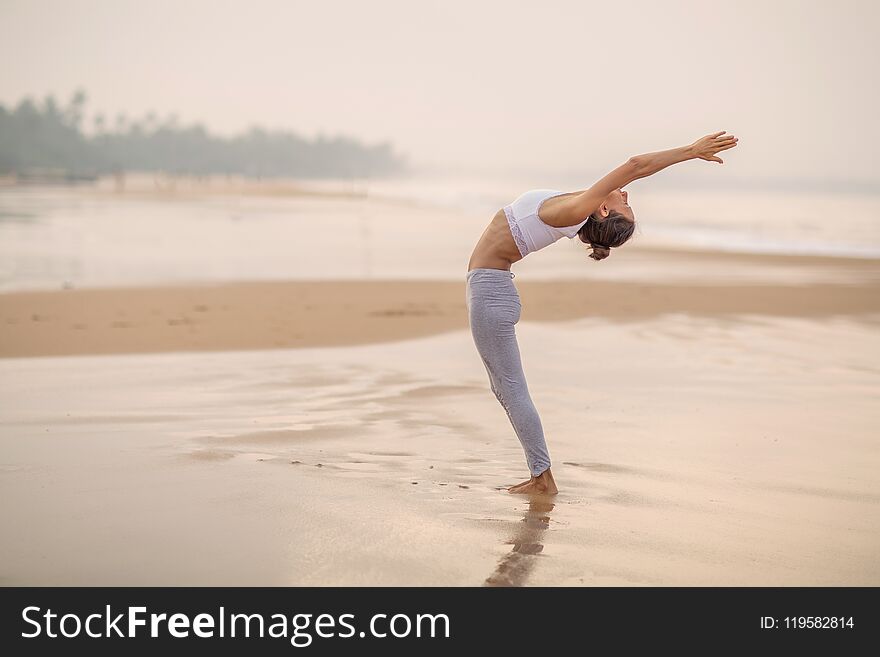 Beautiful woman practicing yoga at seashore of tropic ocean. Beautiful woman practicing yoga at seashore of tropic ocean