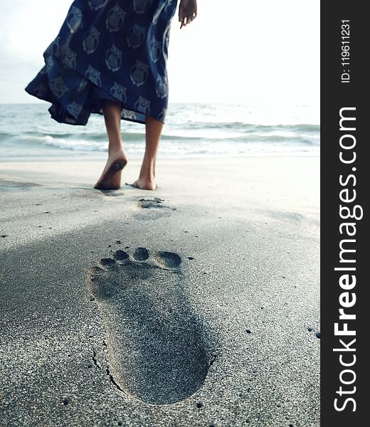 Photo of Woman Walking Barefoot on Seashore