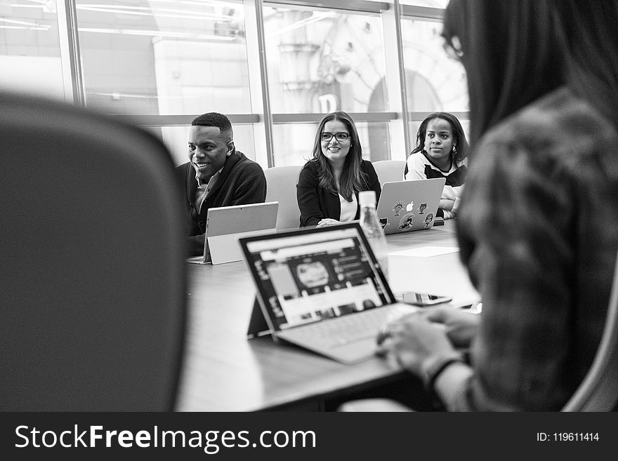 Grayscale Photo of Man and Woman Sitting Infront of Table