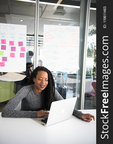 Woman in Gray Sweater Sitting in Front of Laptop Computer on Table