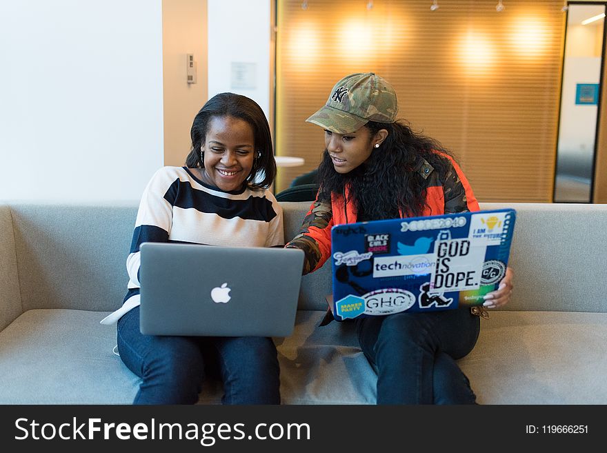 Two Woman Sitting On Sofa While Using Laptops