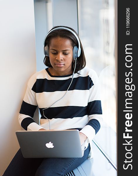 Woman Listening Through Headphones Using Macbook