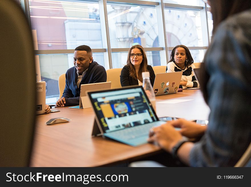 Group Of People Sitting In Front Of Table