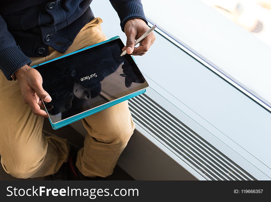 Person Wearing Brown Pants Holding Black Tablet Computer