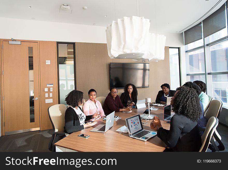 People Sitting Around Brown Wooden Table Under White Pendant Lamp Inside Room