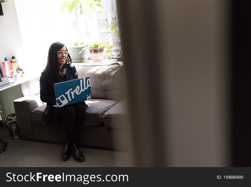 Woman Using Blue and White Laptop Sitting on Sofa