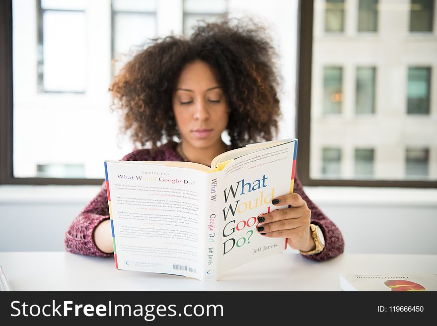 Sitting Woman While Reading Books Near Table