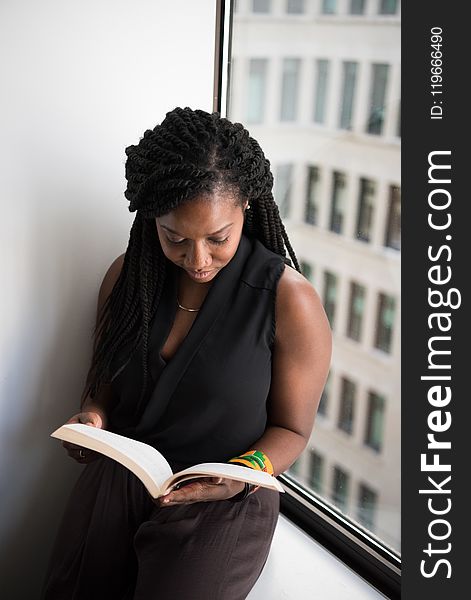 Woman Reading Book Leaning Near Wall