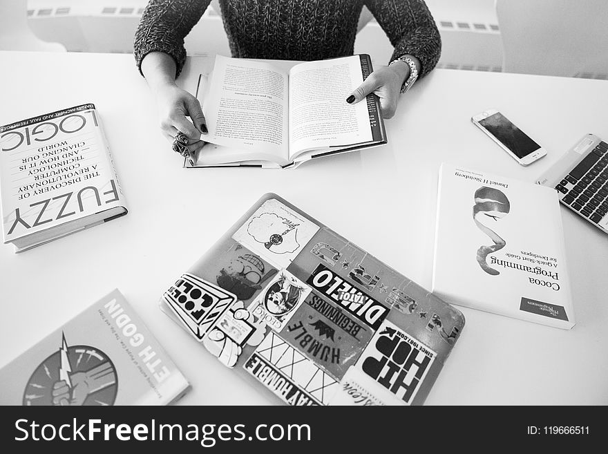 Grayscale Photo Of Person Sitting Near Table With Books