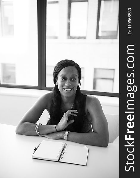 Grayscale Photography of Woman in Sleeveless Top Sits Near Table