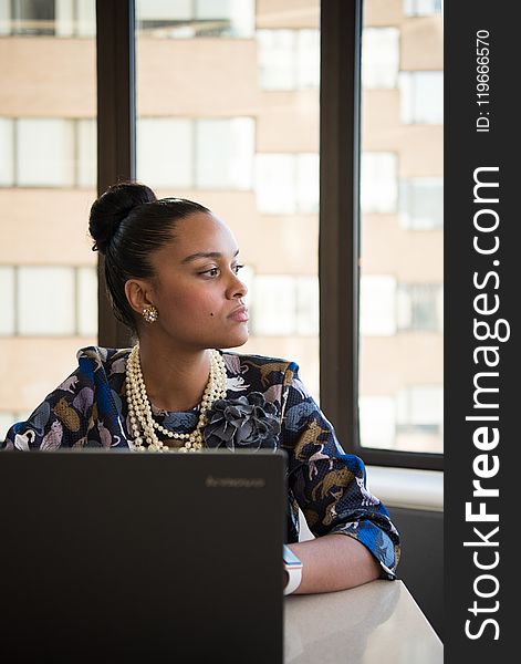 Woman Wearing Blue And Brown Floral Elbow-sleeved Dress Facing Black Lenovo Laptop Near Glass Window