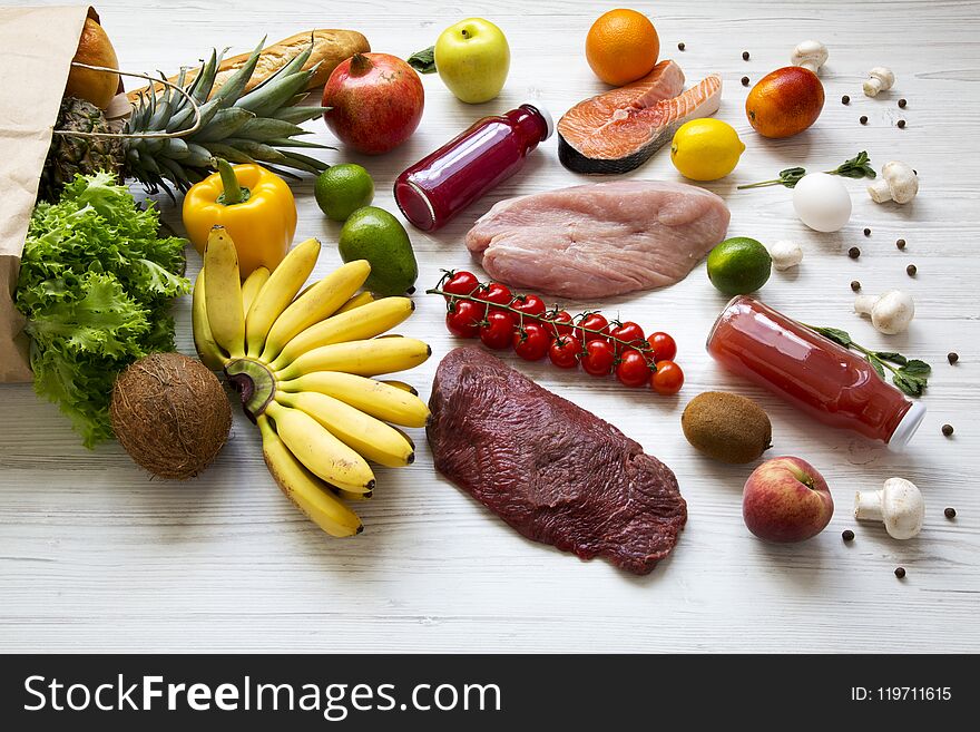 Full paper bag of various healthy food over white wooden background
