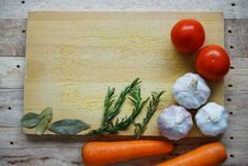 Many Fresh Ingredients, Rosemary, Spaghetti, Carrot, Tomato, Garlic, Onion And Bay Leaf On Chopping Board With Wooden Table Backgr Stock Images