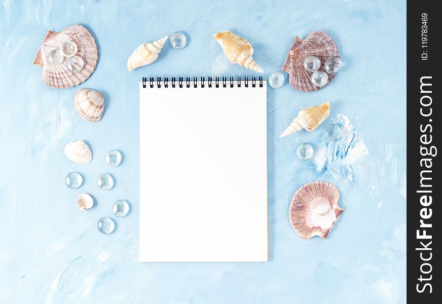 Mock up with frame of seashell and notepad on blue stone background, scallop shell, copy space. Summer concept of holiday by sea. Mock up with frame of seashell and notepad on blue stone background, scallop shell, copy space. Summer concept of holiday by sea