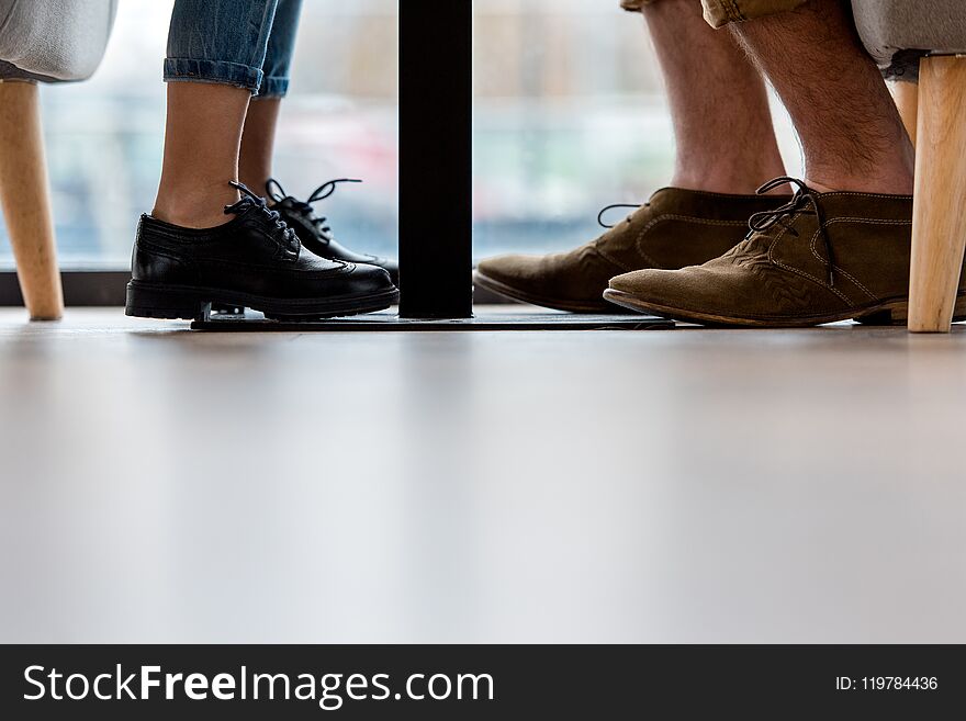 cropped image of father and daughter legs under table