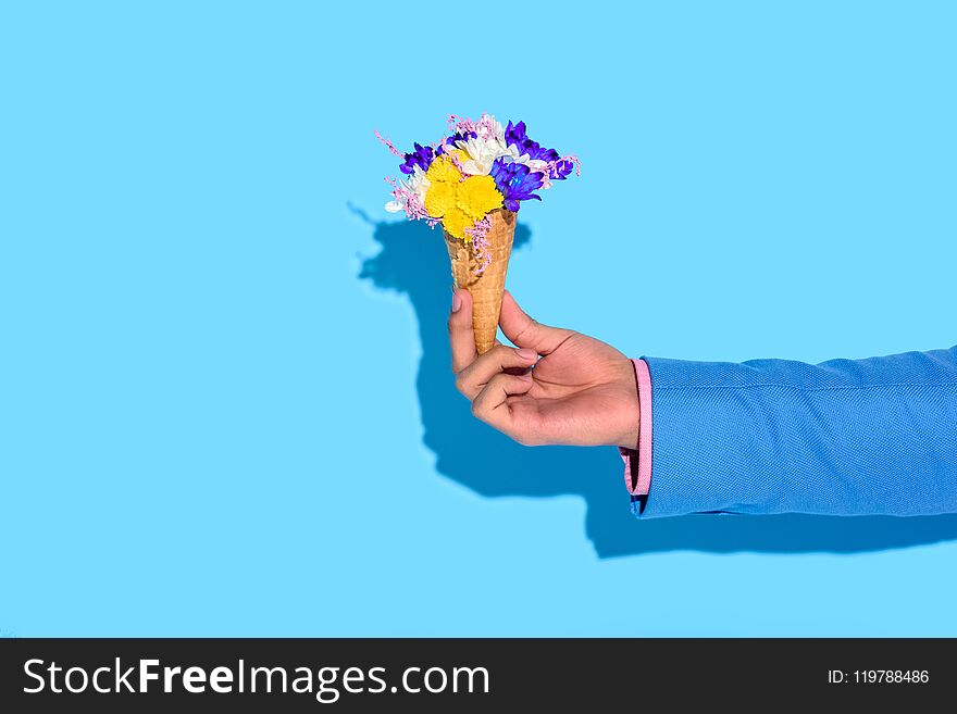 Cropped image of man hand holding flowers on blue background