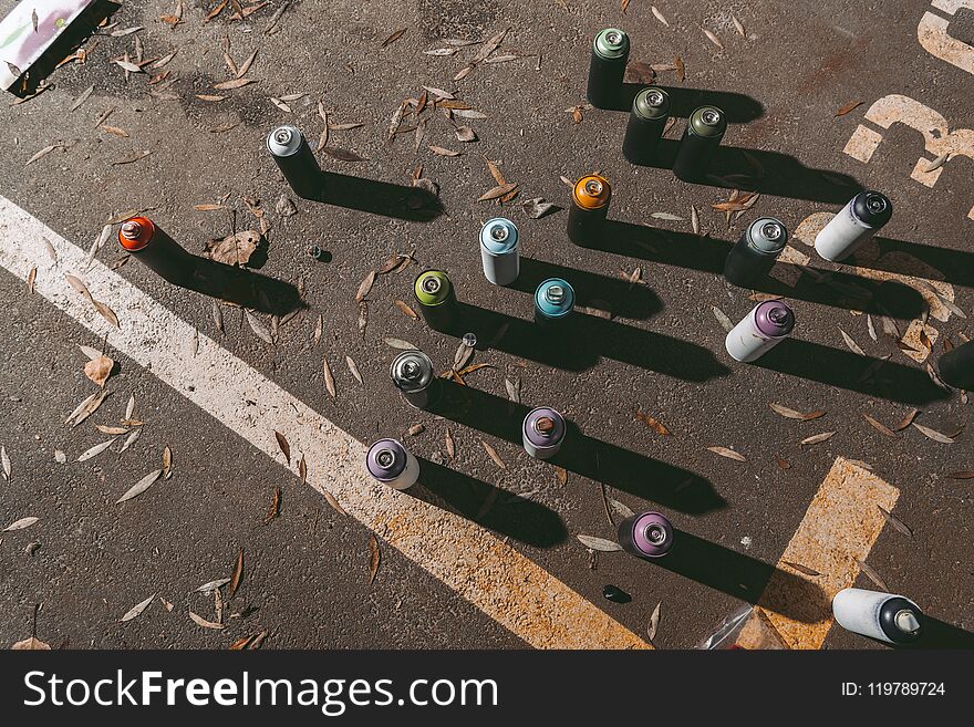 top view of cans with colorful spray paint for graffiti on asphalt
