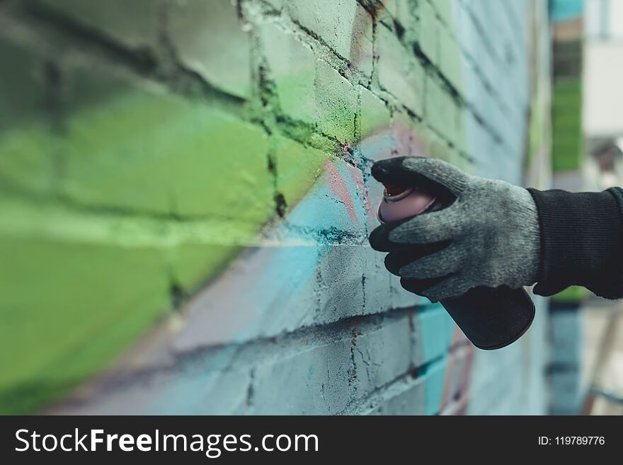 cropped view of man painting colorful graffiti on wall