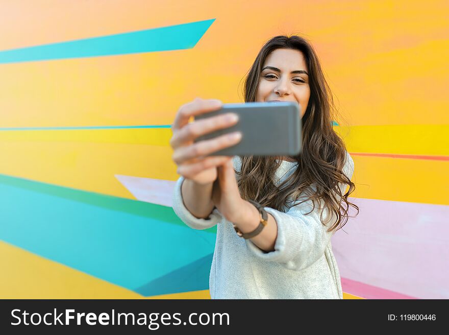 Hipster woman taking selfie photos in colorful abstract background. Hipster woman taking selfie photos in colorful abstract background