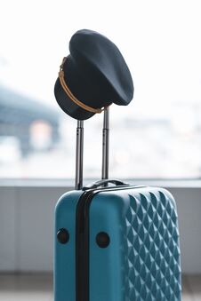 Pilot Cap Hanging On Handle Of Suitcase Stock Photo