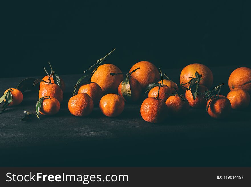 close up view of ripe mandarins with leaves on wooden tabletop