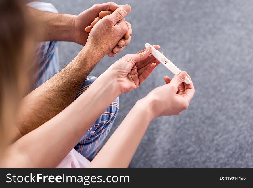 partial view of couple with pregnancy test