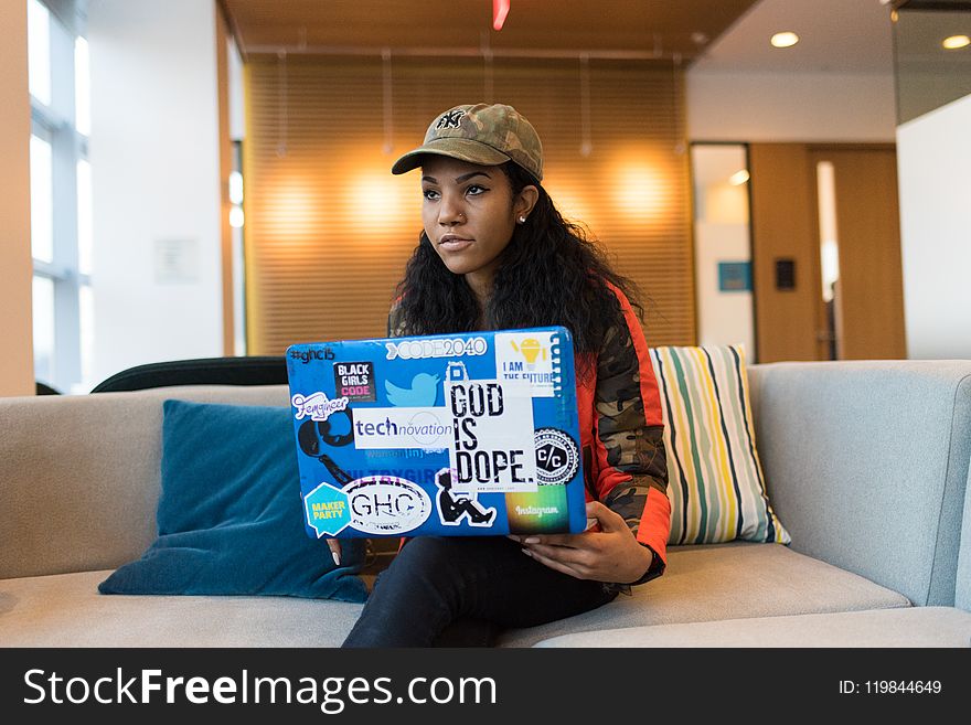 Woman Holding Blue Box While Sitting on White Couch