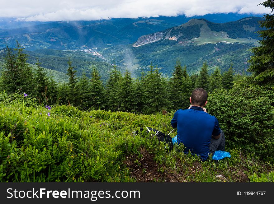 Man Wearing Blue Shirt Sitting On Green Grass