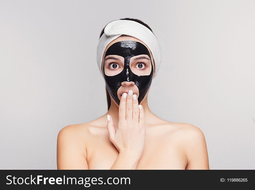 Skin care. Portrait of young girl with black mask on face. Purifying spa treatment, white studio background, copy space. Skin care. Portrait of young girl with black mask on face. Purifying spa treatment, white studio background, copy space