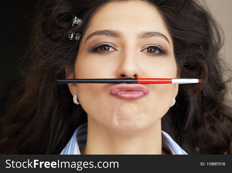 Young model holds a makeup brush in the form of a mustache in hairstyle and makeup salon. little fun during the long