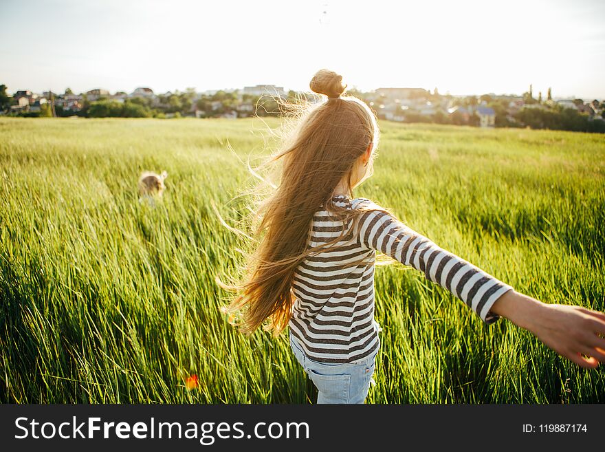 Cheerful girls are playing catch-up in the green field at sunset. Children`s games during the summer holidays in the village. Cheerful girls are playing catch-up in the green field at sunset. Children`s games during the summer holidays in the village.