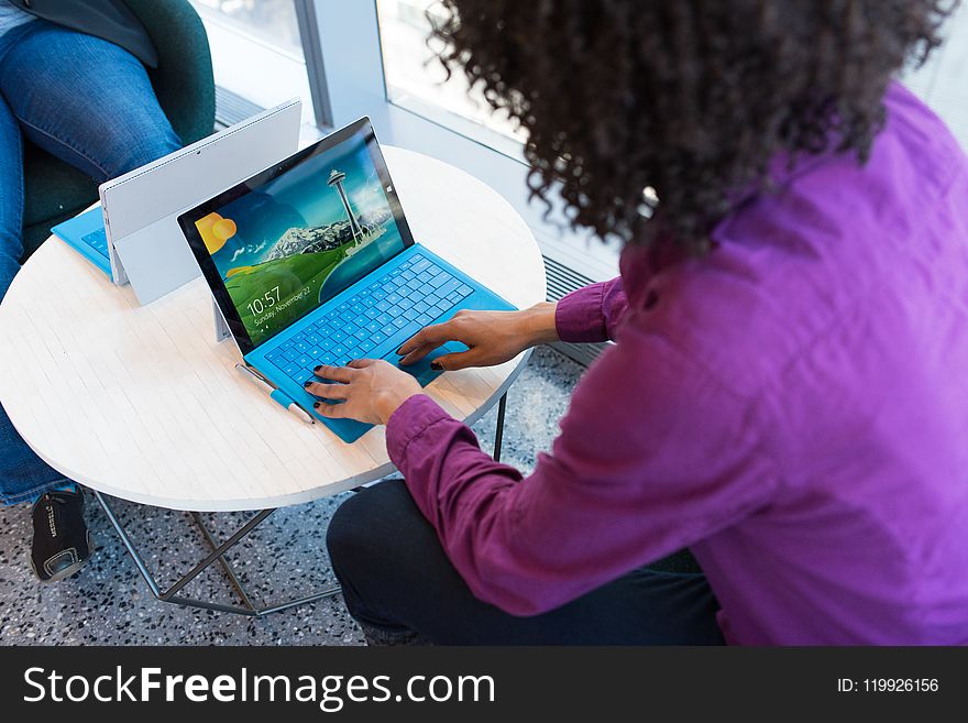 Person Using Blue Laptop Sitting Beside Table