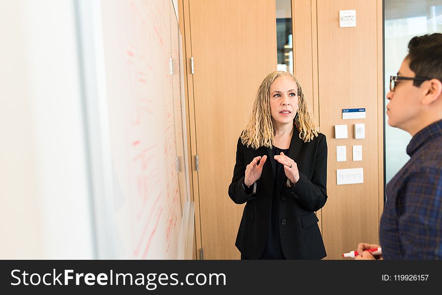 Woman Wearing Suit Jacket Standing In Front Of Whiteboard