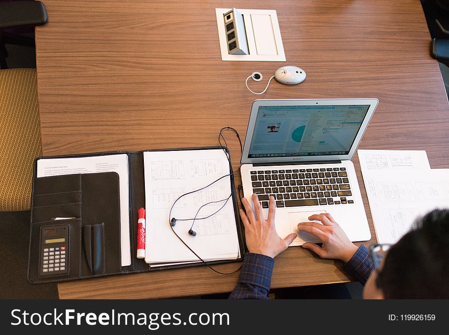 Person In Blue Dress Shirt Facing White Laptop On Brown Wooden Table