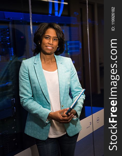 Woman in Teal Blazer Coat and Black Pants Holding A Tablet