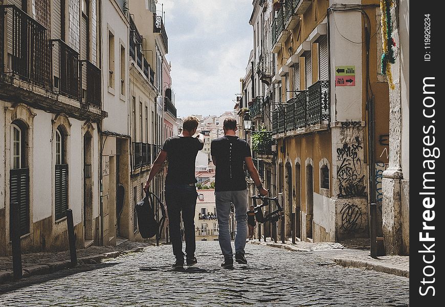 Two Man Walking In Between Of Buildings Toward With Concrete Building