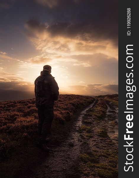 Man Standing In Muddy Field Path.