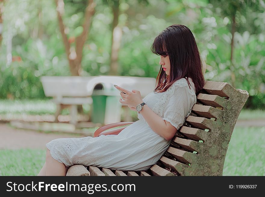 Woman Wearing White Dress Sitting on Bench