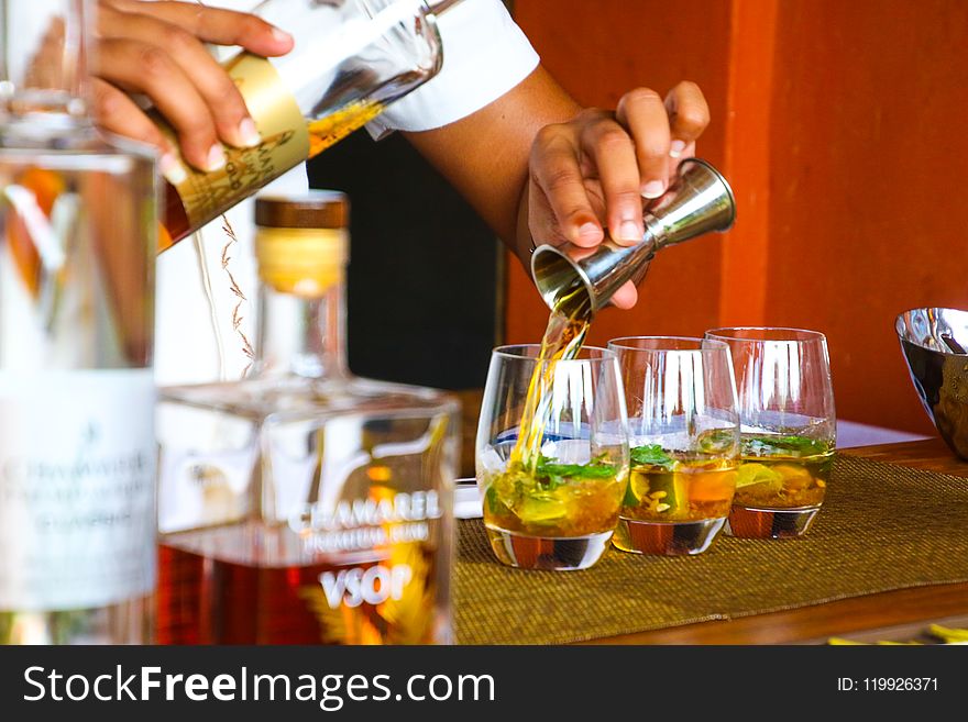 Person Poring Cocktail On Clear Drinking Glass