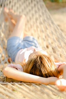 Close Up Young Girl Lying In White Wicker Hammock On Sand, Wearing Jeans Shorts. Royalty Free Stock Photography