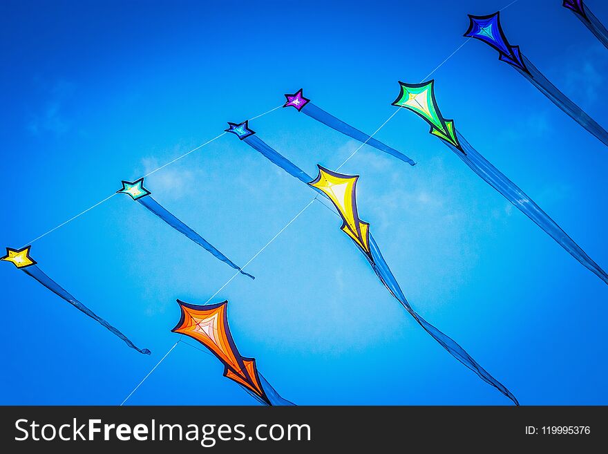 Brightly colored flying kites against a summer blue sky