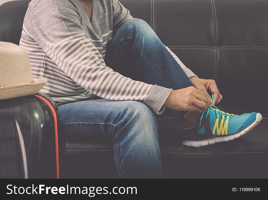 Female traveller tying shoe rope on leather sofa in the airport. Travel concept. Female traveller tying shoe rope on leather sofa in the airport. Travel concept.